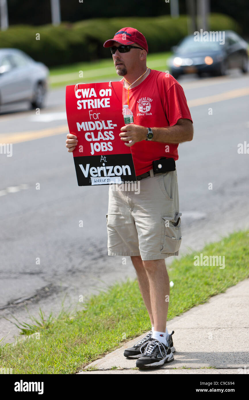 An on-strike Verizon employee pickets on the street in front of a Verizon Wireless store Stock Photo