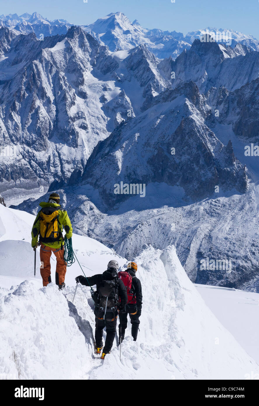 A mountain guide leads two mountaineers along the arete leading from the summit of the Aiguille du Midi Stock Photo