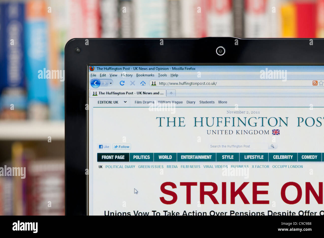 The Huffington Post website shot against a bookcase background (Editorial use only: print, TV, e-book and editorial website). Stock Photo