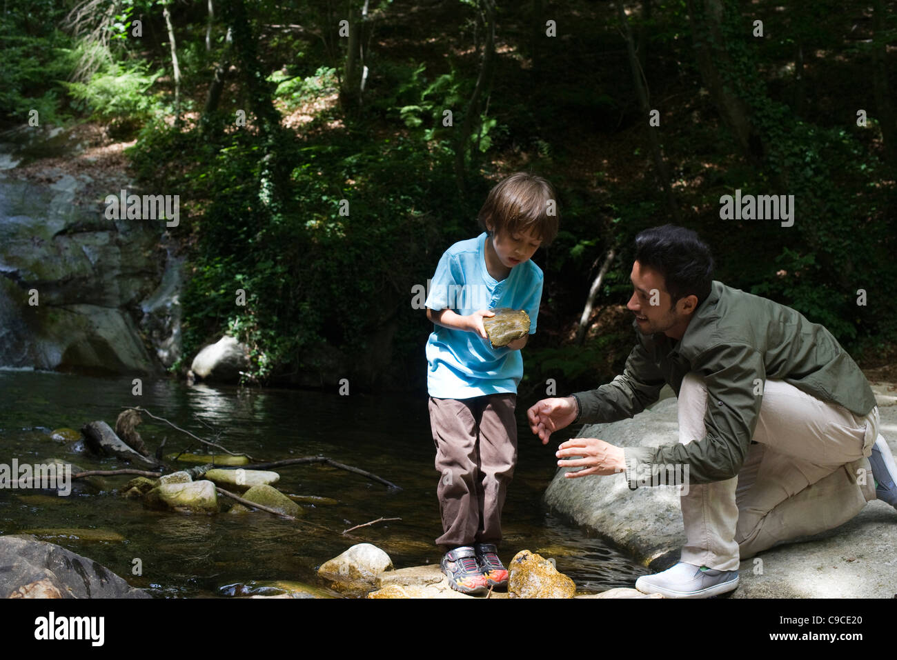 Father and son exploring nature, boy holding rock Stock Photo