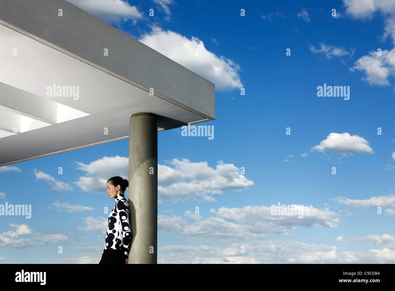 Fashionably dressed young woman leaning against portico column Stock Photo