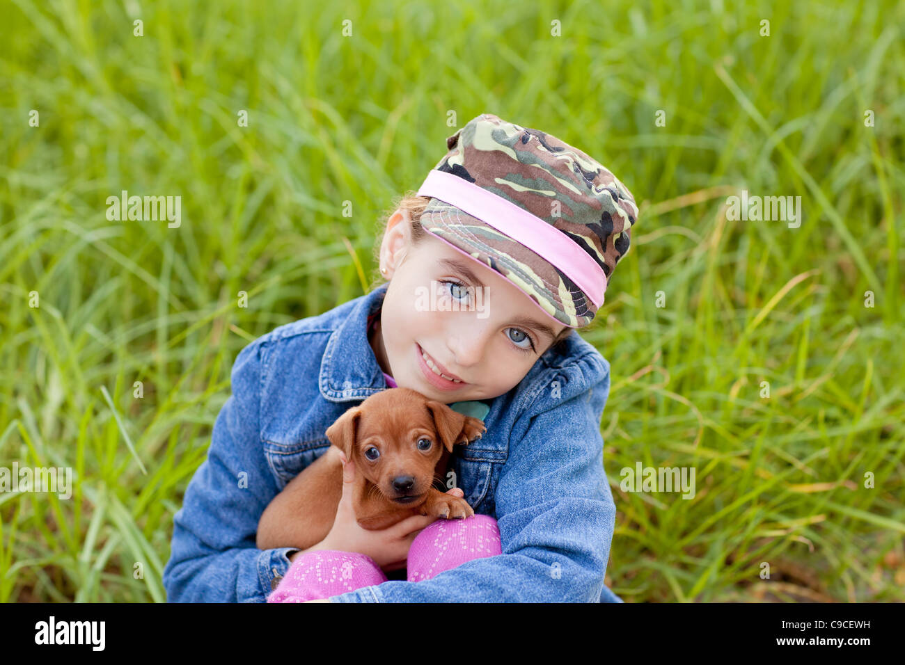 little girl with pet puppy mascot mini pinscher in outdoor green grass ...