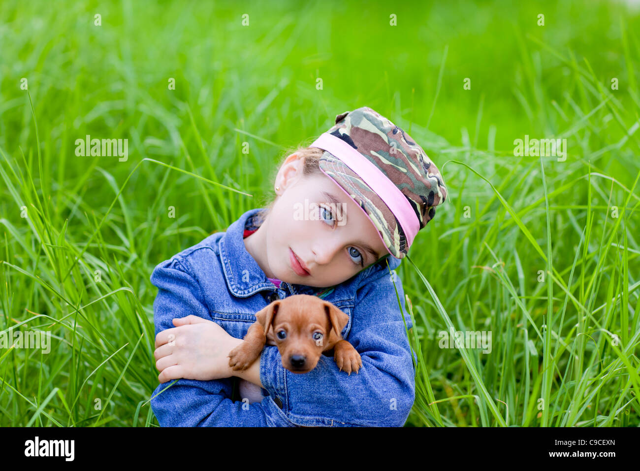 little girl with pet puppy mascot mini pinscher in outdoor green grass ...