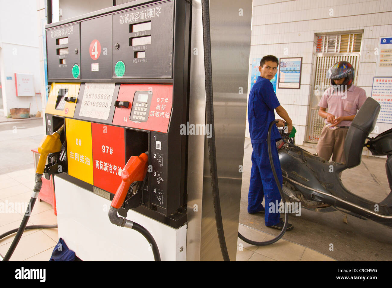 PAN YU, GUANGDONG PROVINCE, CHINA - Gas pump at service station. Attendant fills scooter tank for customer. Stock Photo