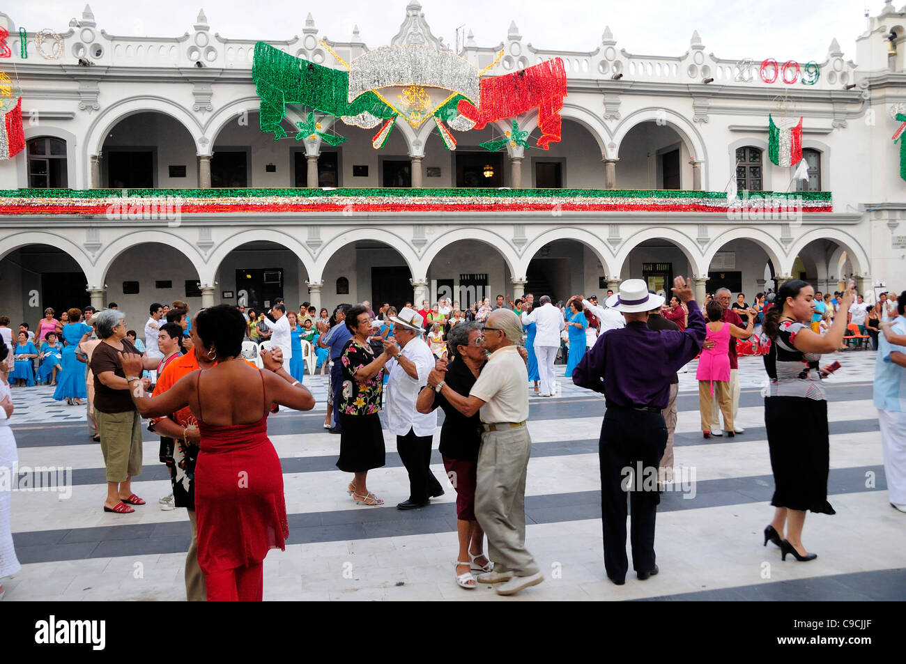 Mexico, Veracruz, Couples dancing in the Zocalo with facade of government buildings behind hung with bright decorations Stock Photo