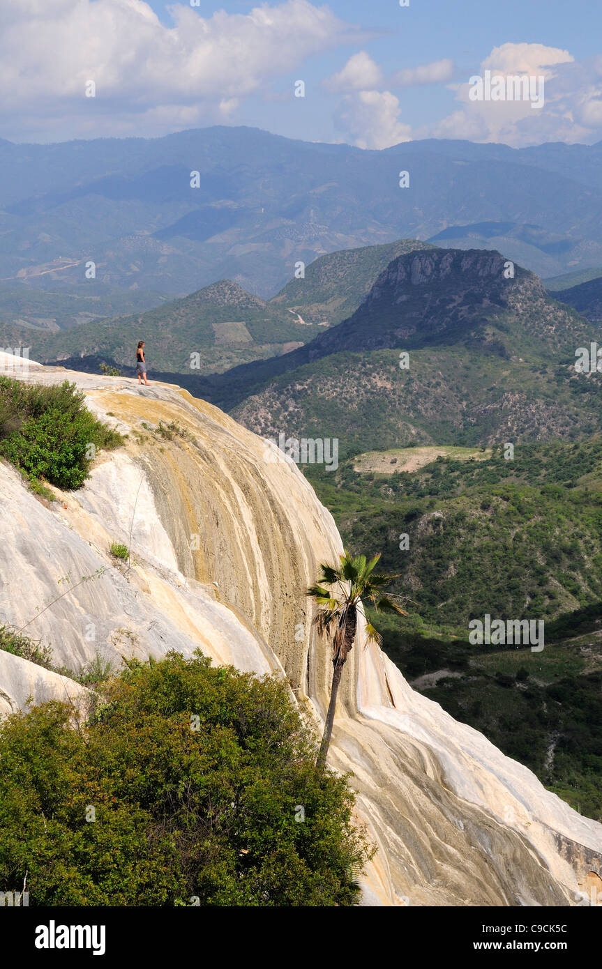 Mexico, Oaxaca, Hierve el Agua, Tourist standing on limestone cliff looking out over surrounding landscape. Stock Photo