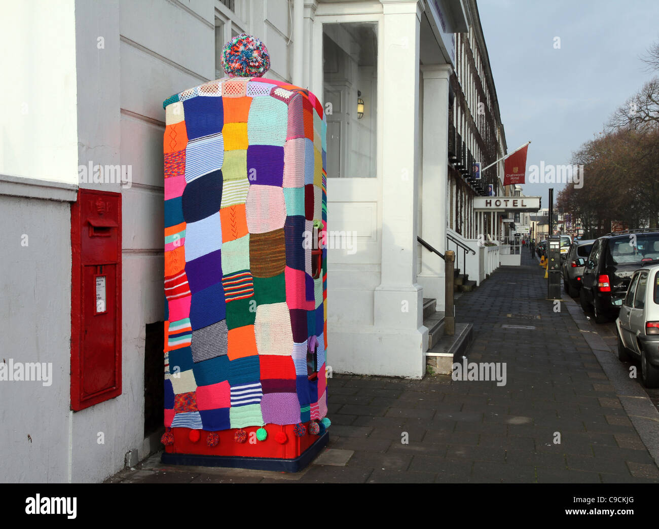 A red public telephone kiosk that had been covered over with knitting like a big tea cosy. Stock Photo