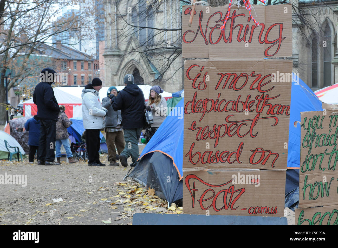 November 21, 2011, unidentified protesters discuss matters today at St. James Park Toronto following the decision handed down this morning by Ontario Superior Court judge David Brown, upholding the Occupy Toronto tent camp eviction.  A hand painted sign, right quotes Albert Camus. Stock Photo
