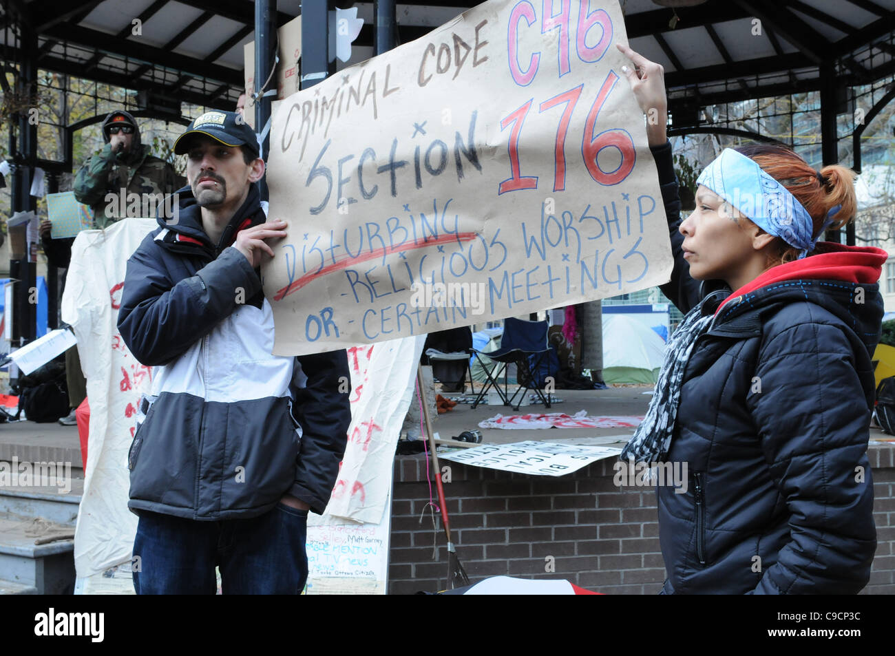 November 21, 2011, two unidentified native protesters hold up a sign citing Canada's criminal code at St. James park following the decision handed down this morning by Ontario Superior Court judge David Brown, upholding the Occupy Toronto tent camp eviction. Stock Photo