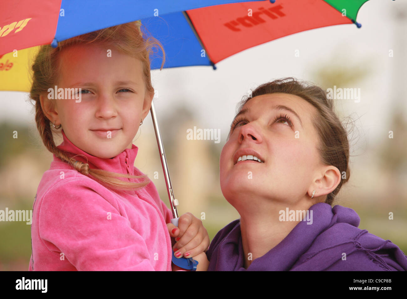 girl and mom are hiding under the umbrella of color fall Stock Photo