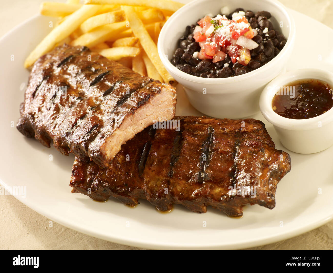 Baby back rib dinner with black beans and french fries Stock Photo