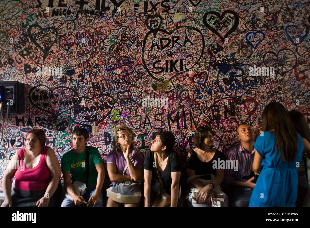 Tourists sit beneath graffiti on a wall at the entrance to the Casa di Giulietta in Verona, Italy Stock Photo