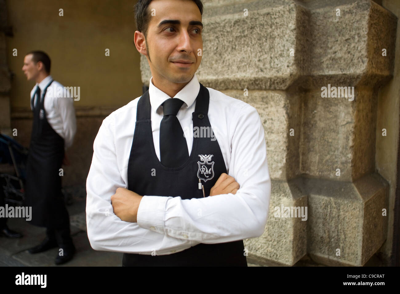 A waiter from a restaurant waits on the street in Verona, Italy Stock Photo
