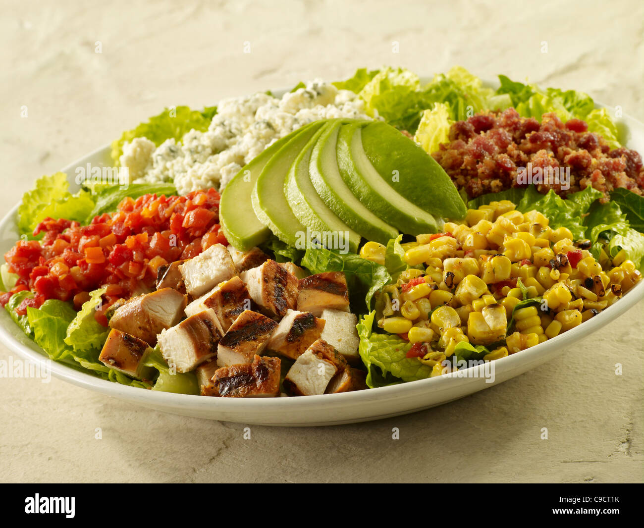 Chopped grilled chicken salad with bacon, corn, cheese, tomato, lettuce and sliced avocado Stock Photo