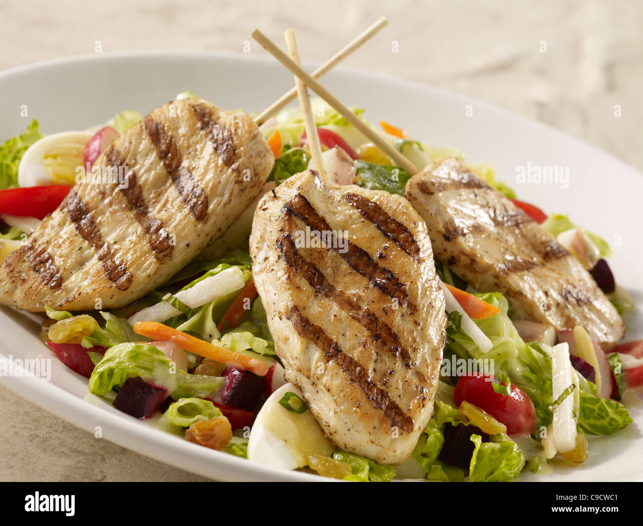 Grilled chicken salad with lettuce, egg, carrot, tomato and onion with dressing Stock Photo
