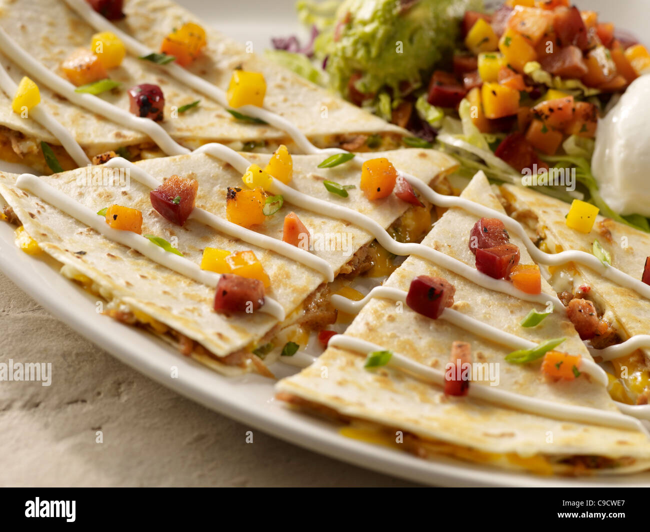A carnitas quesadilla topped with salsa and served with sour cream and guacamole Stock Photo