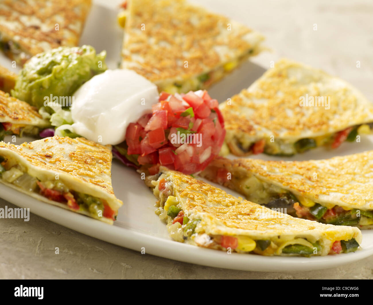 A vegetable quesadilla with salsa fresca, sour cream and guacamole