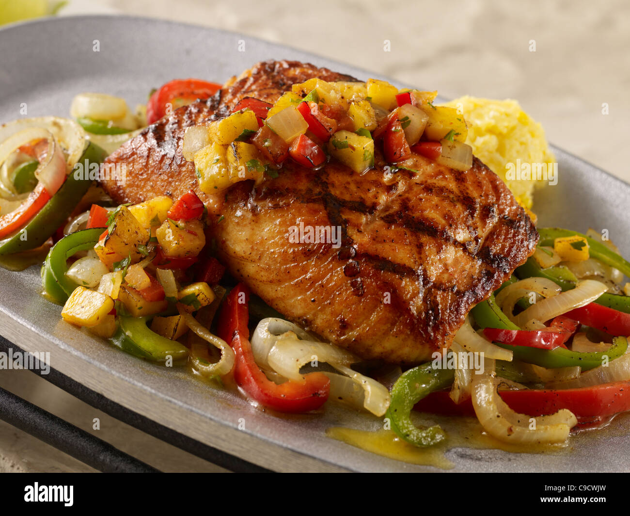 Grilled salmon fillet topped with pineapple salsa over fajita vegetables Stock Photo