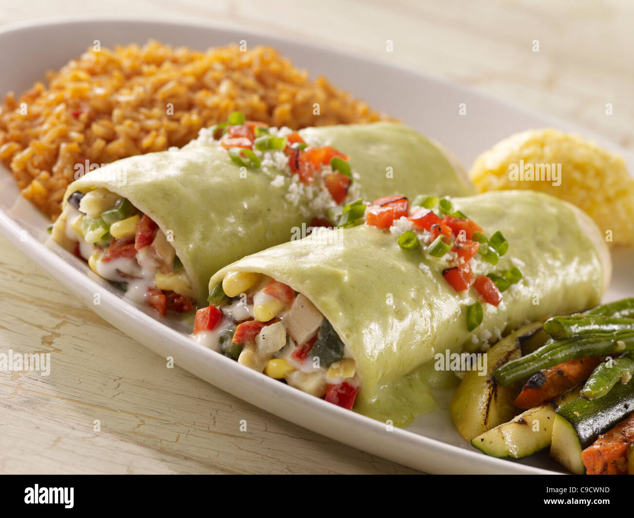 Two vegetable enchiladas topped with creamy green sauce and served with