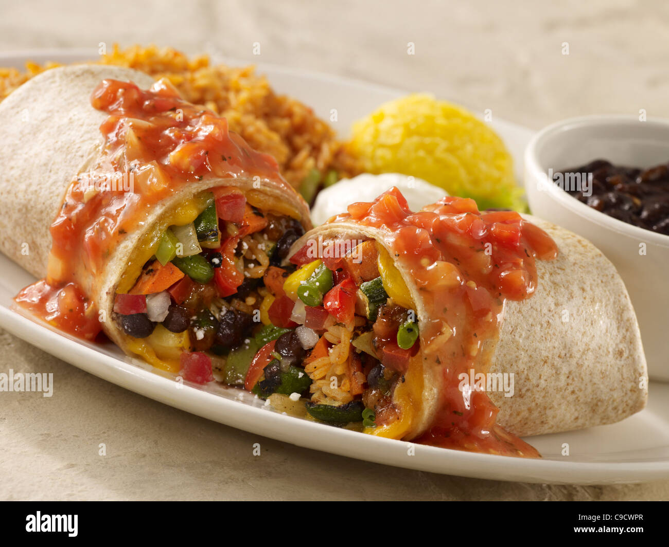 A vegetable burrito topped with salsa and sour cream and served with