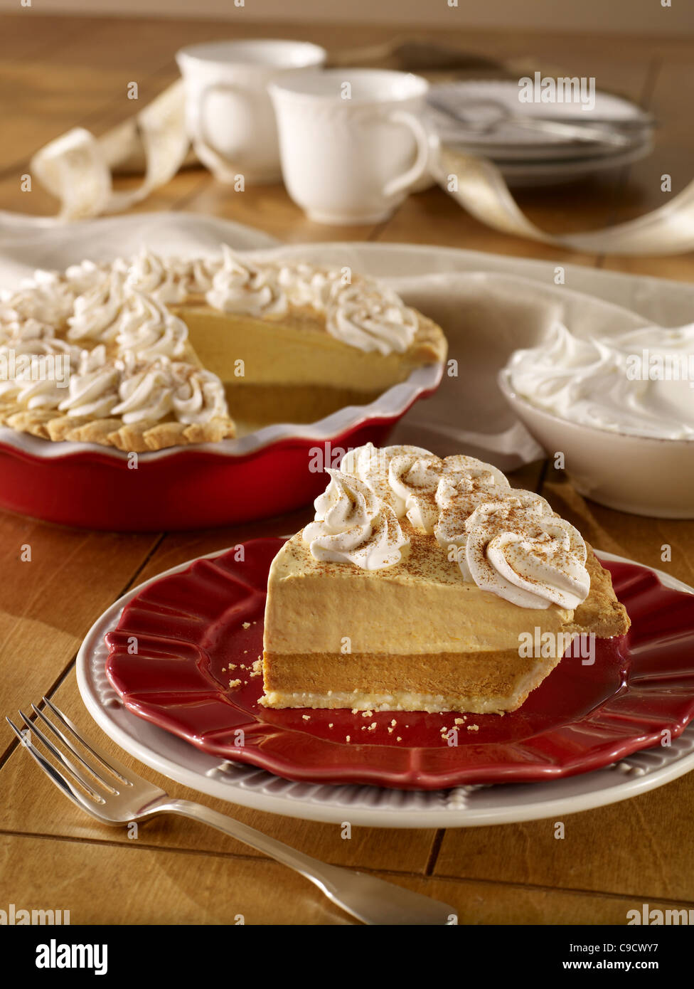 A whole pumpkin cream pie with a slice topped with whip cream Stock Photo
