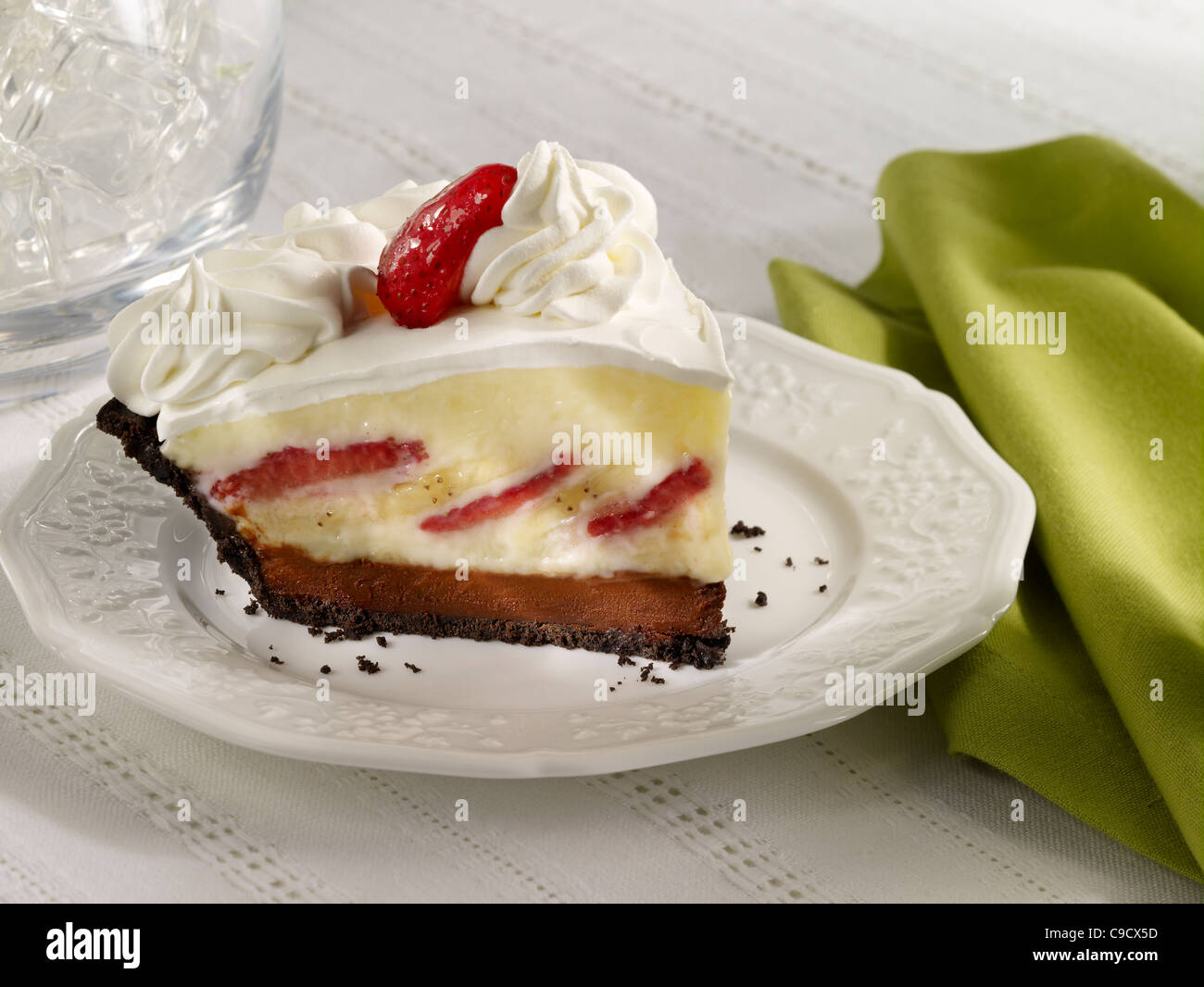 Strawberry Banana Cream Pie with Whip Cream and a strawberry on a white plate Stock Photo