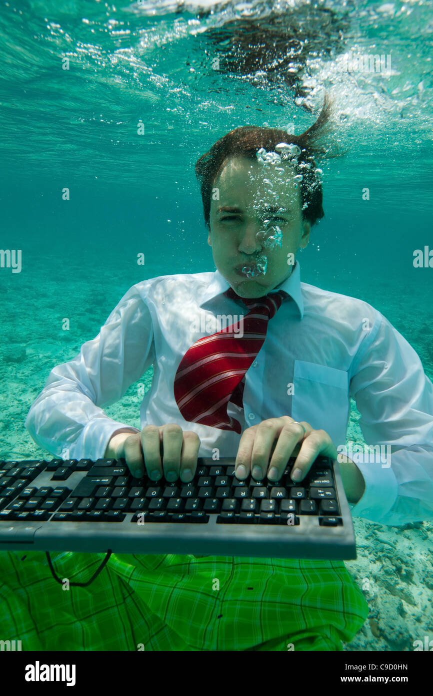 Young businessman with keyboard in formal clothes working underwater