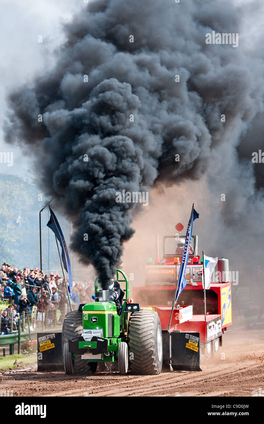 Tractor straining to haul a weight shifting sled at a tractor pulling contest. Stock Photo