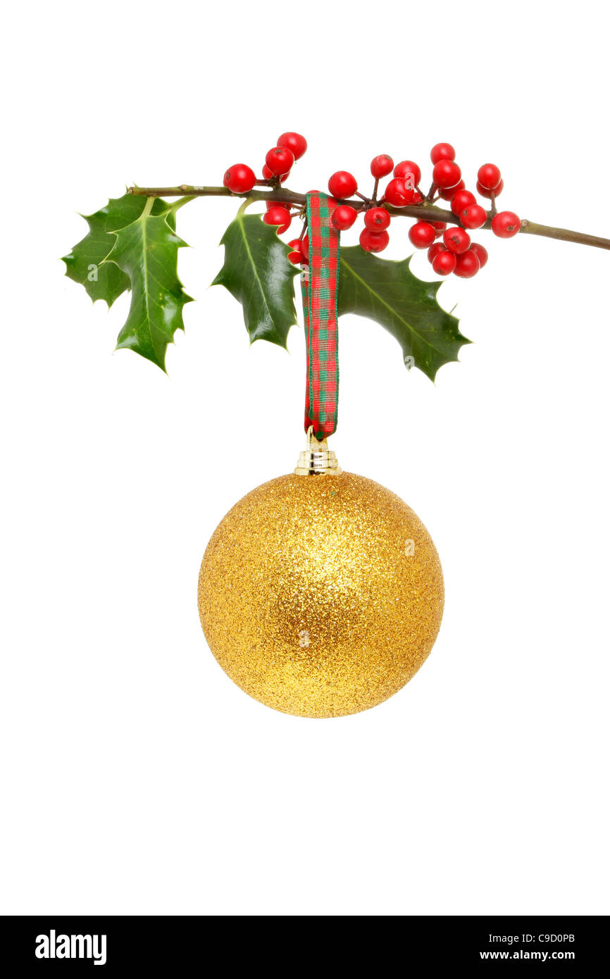 Golden glitter Christmas ball hanging from a holly branch bearing red ripe berries Stock Photo