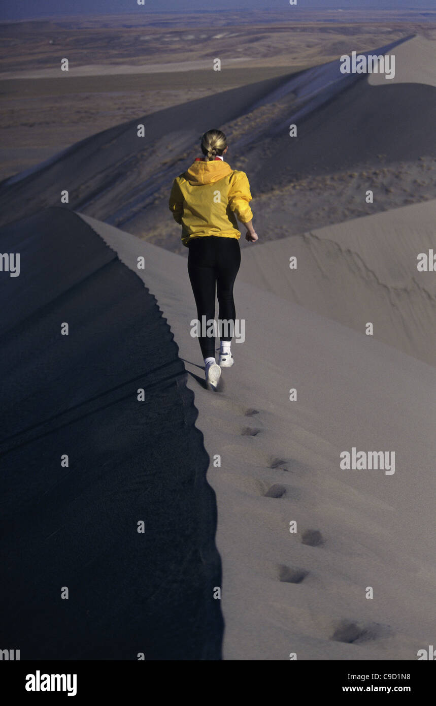 Rear view of a young woman running on a sand dune Stock Photo - Alamy