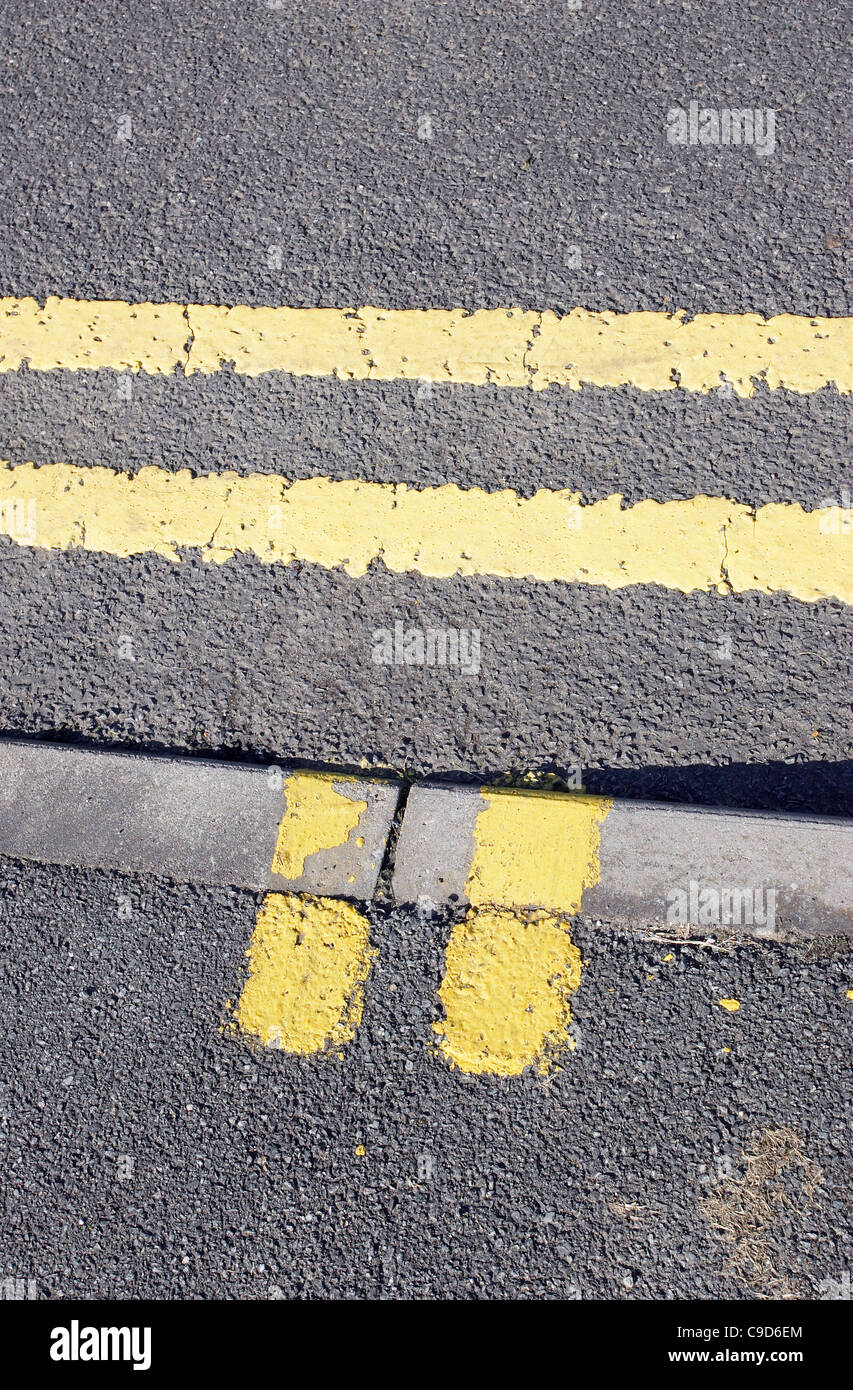 Double yellow parking and loading restriction lines painted on a road and curb. Stock Photo