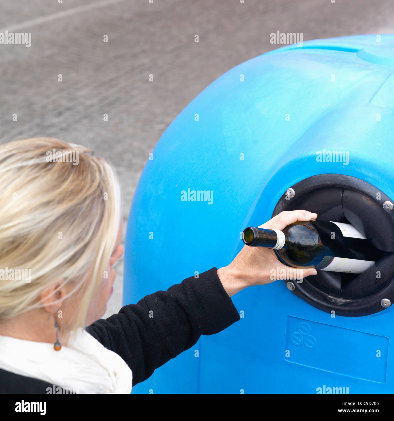 Italy, Piedmont, Woman dropping bottle into recycling bin Stock Photo