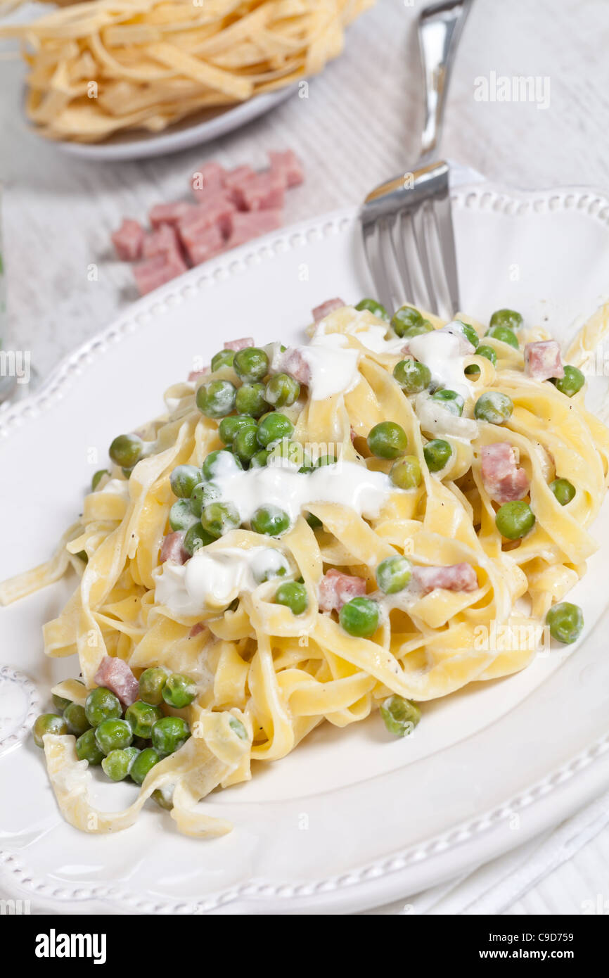 Egg noodles with cream, ham and green peas Stock Photo Alamy