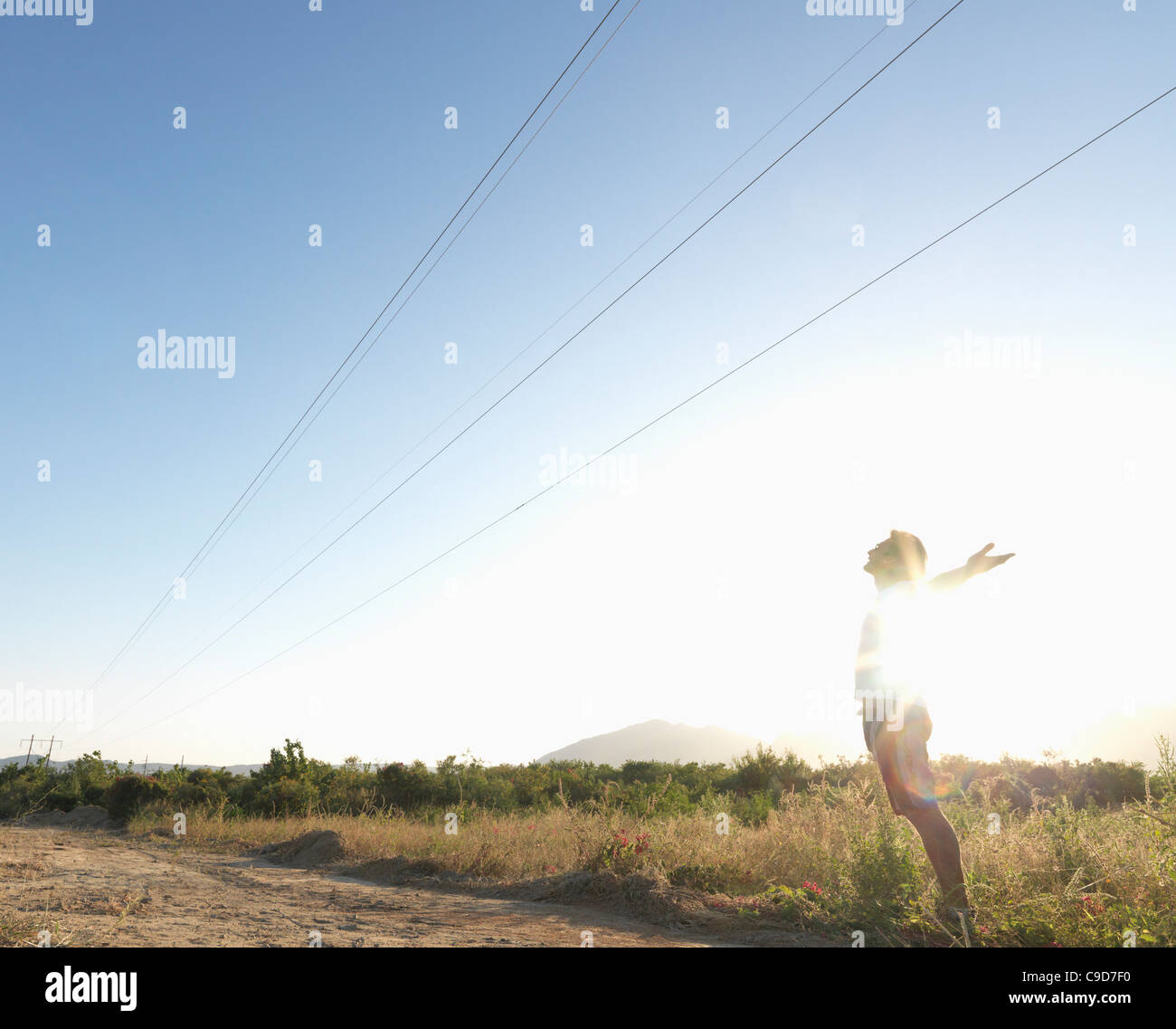 Mexico, Baja California, Man standing under power lines in desert with ...