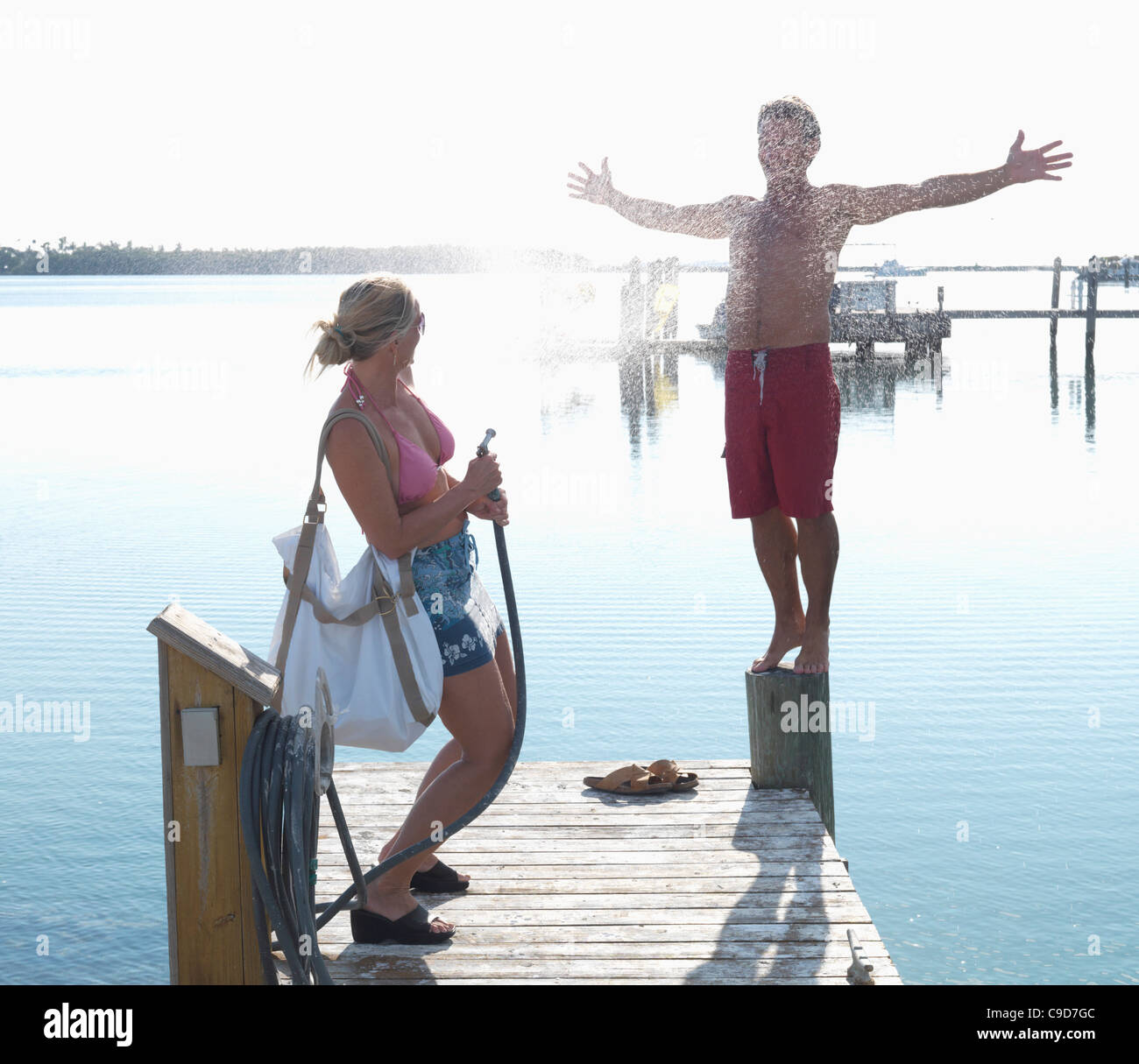 USA, Florida Keys, Islamorada, couple playing with water spray on pier ...