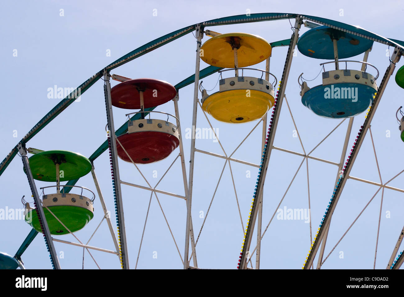 Colorful cars with canopies on a fairground ferris wheel ride. Stock Photo