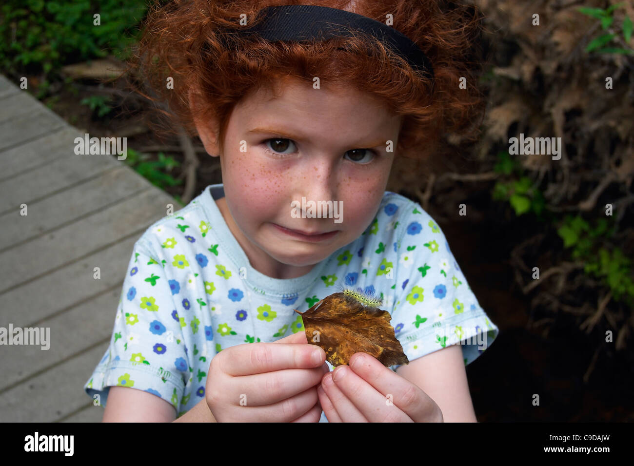 A young girl warily displays a found caterpillar. Stock Photo