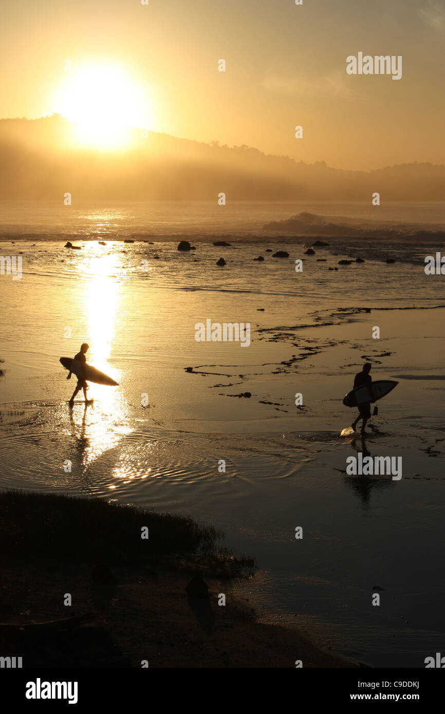 Surfers at sunrise on an Indonesian beach Stock Photo