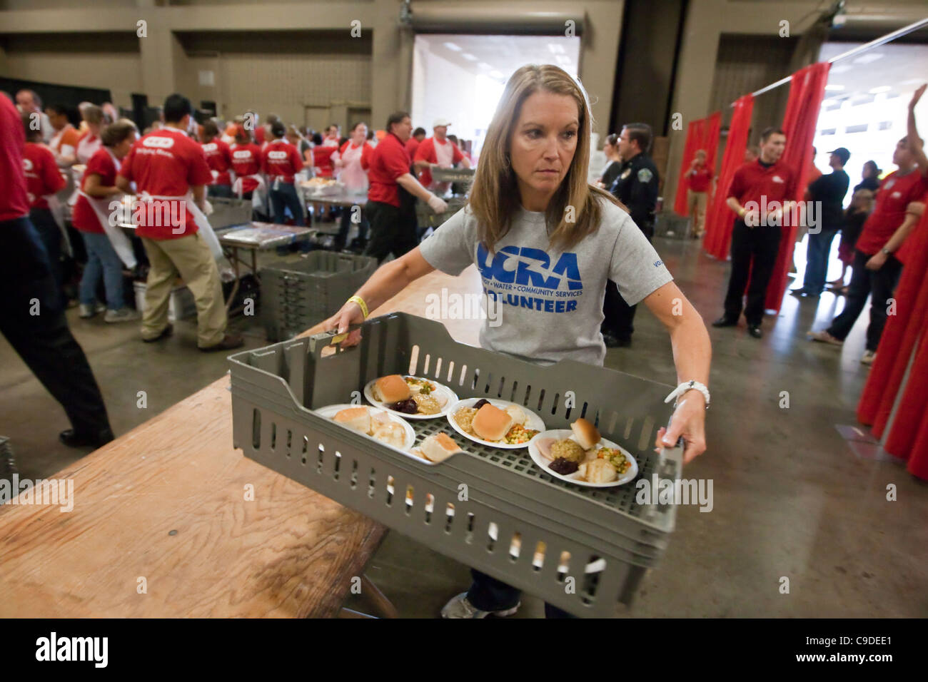 Multi-ethnic group of volunteers help serve hundreds of free Thanksgiving meals donated by large Texas based supermarket chain. Stock Photo