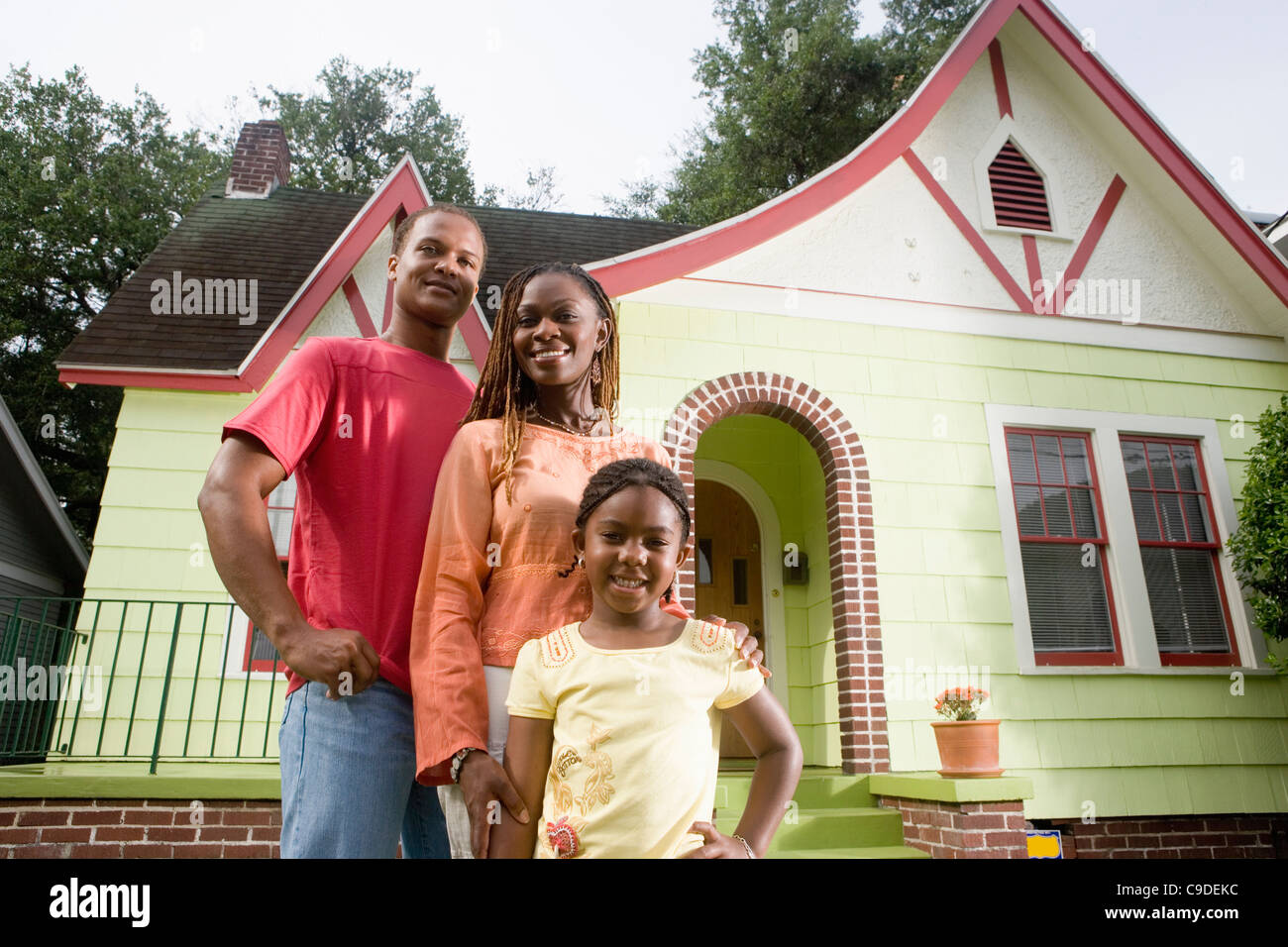 Portrait of young family standing in front of house Stock Photo - Alamy