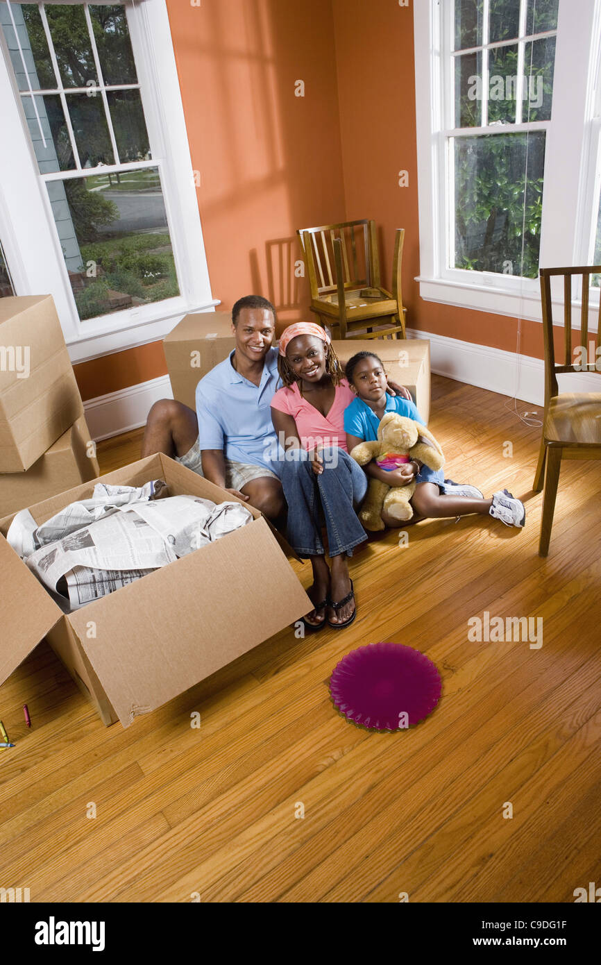 Portrait of family sitting by moving boxes Stock Photo - Alamy