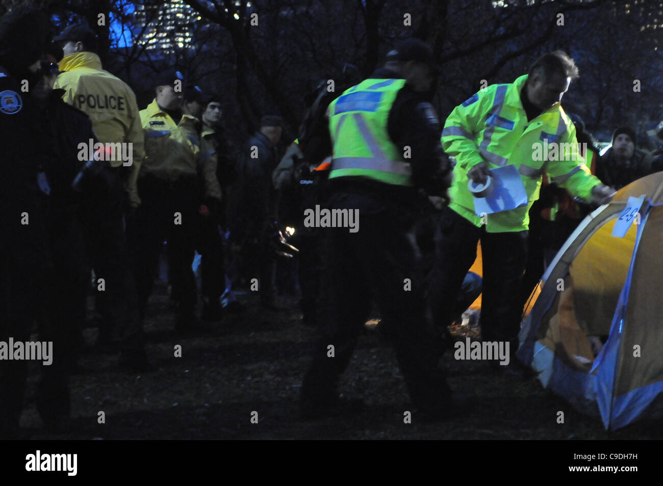 November 23, 2011, Toronto Police deploy in significant numbers before dawn, beginning the process of evicting the Occupy Toronto tent camp from St. James Park.  Here Police and city workers place a numbered sign on a protest tent prior to it's being removed. Stock Photo