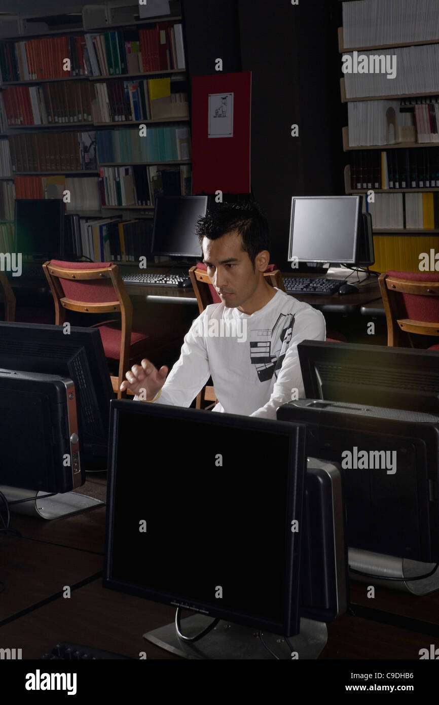 Young man using a computer in the library Stock Photo - Alamy