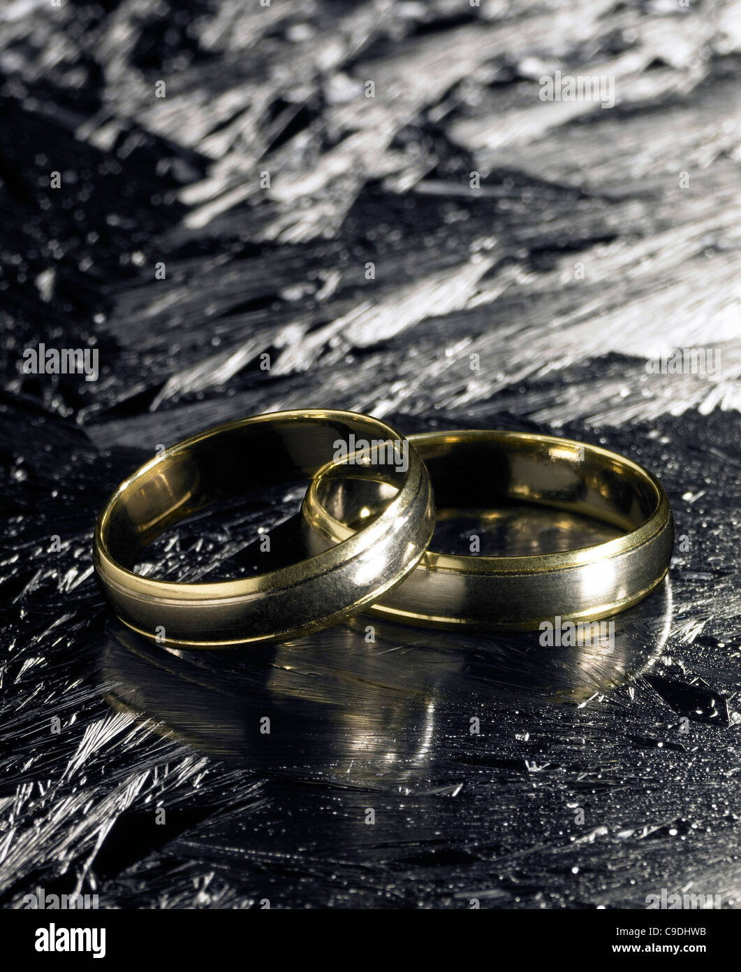 studio photography of two golden wedding rings on each other in icy ...