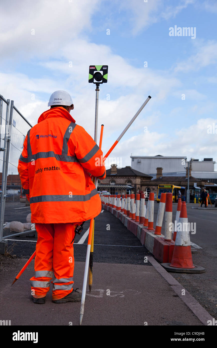 Building surveyor in a Hi-Viz jacket and trousers taking levels. Stock Photo