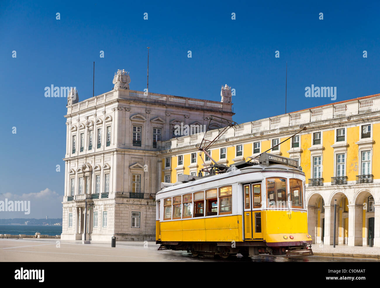historic classic yellow tram of Lisbon built partially of wood in front of Lisbons central square Praca de Comercio, Portugal Stock Photo