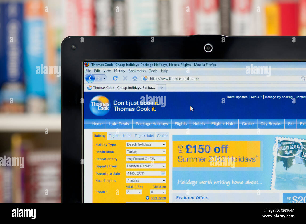 The Thomas Cook website shot against a bookcase background (Editorial use only: print, TV, e-book and editorial website). Stock Photo