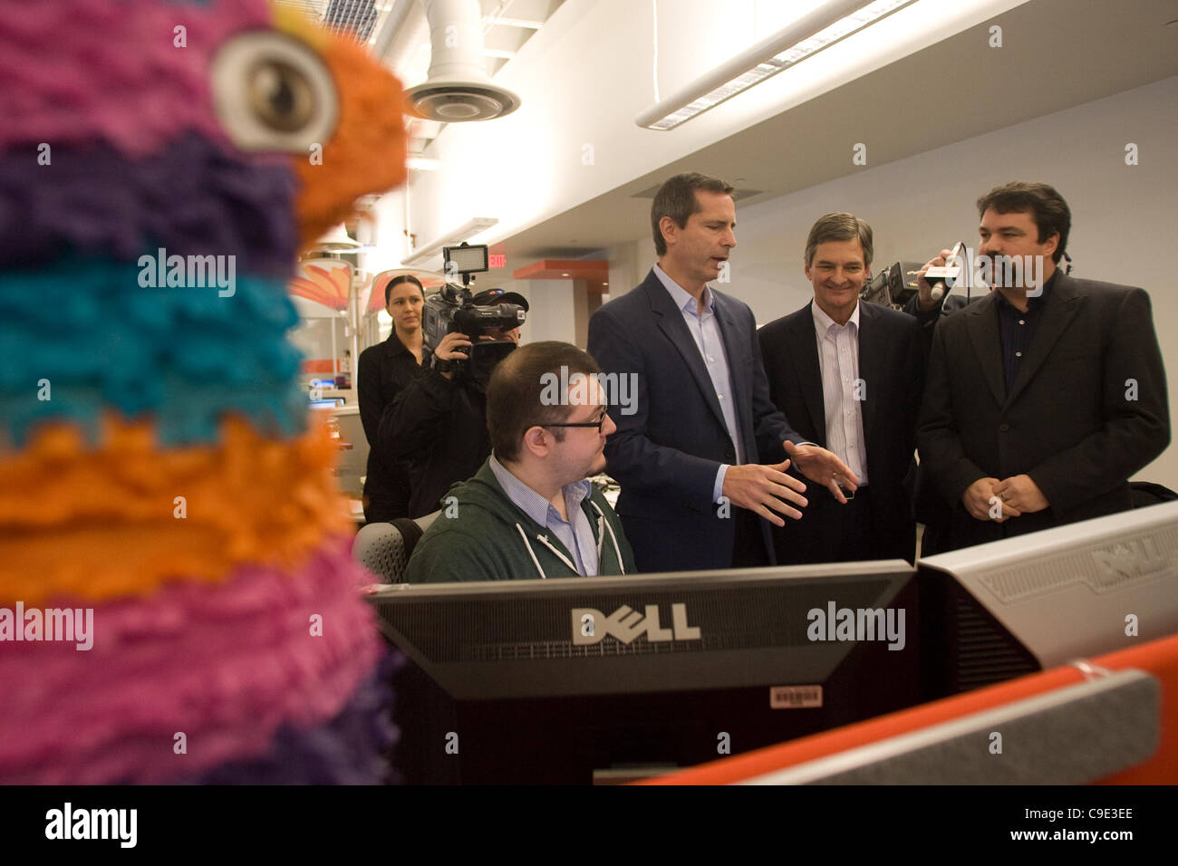 London Ontario, Canada - November 28, 2011. Dalton McGuinty Premier of Ontario speaks with Mukney Tipping, a designer with Digital Extremes (seated) Chris Bentley, MPP for London West, second from right and James Schmalz, president and founder or Digital Extremes, right. McGuinty was touring the off Stock Photo