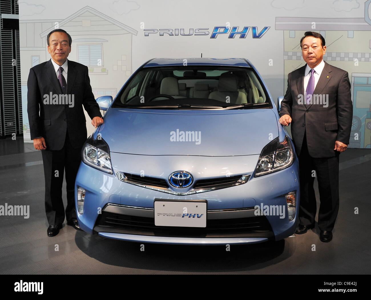 November 29, 2011, Tokyo, Japan - Takeshi Uchiyamada, left, and Shinichi Sasaki, both Toyota Motor Corp.s vice presidents, pose for photographers with the Prius PHV during a launch in Tokyo on Tuesday, November 29, 2011. The gasoline-electric hybrid vehicle can be charged using a household electric. Stock Photo