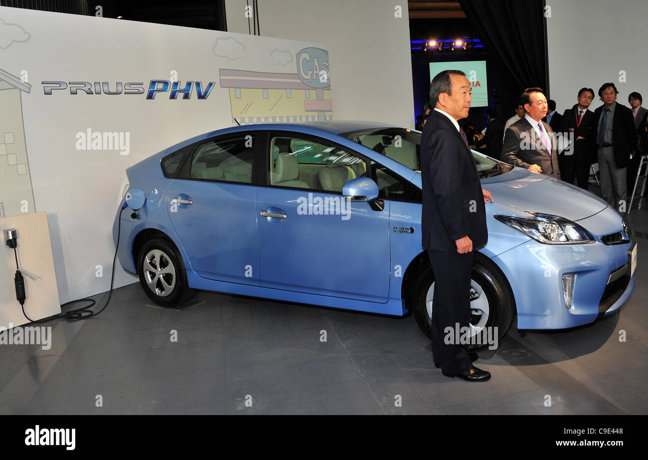 November 29, 2011, Tokyo, Japan - Takeshi Uchiyamada, left, and Shinichi Sasaki, both Toyota Motor Corp.s vice presidents, pose for photographers with the Prius PHV during a launch in Tokyo on Tuesday, November 29, 2011. The gasoline-electric hybrid vehicle can be charged using a household electric. Stock Photo